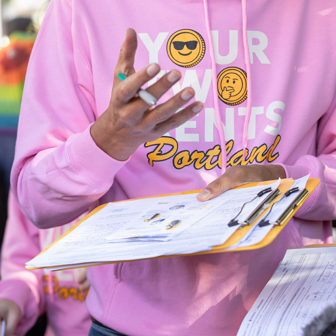 Your 2 Cents Portland volunteer holding a clipboard